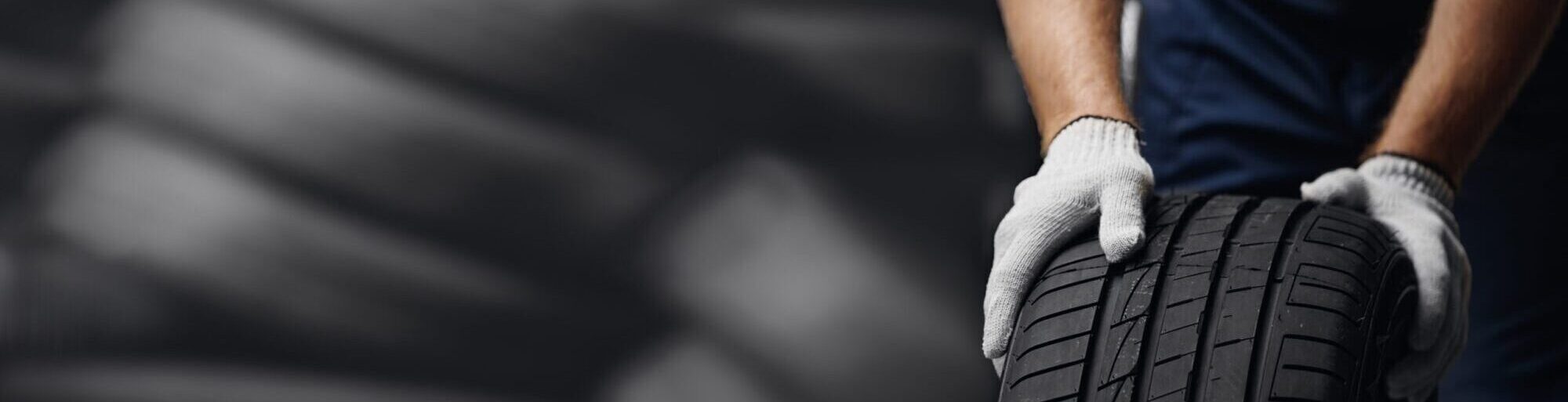 Portrait,Man,Mechanic,Holding,New,Tyre,On,Background,Store,,Car